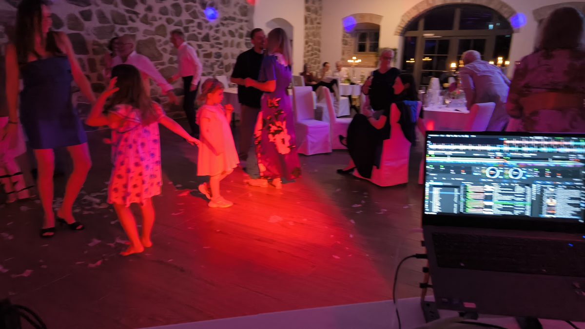 Volle Tanzfläche mit feiernden Gästen, im Vordergrund das DJ-Pult