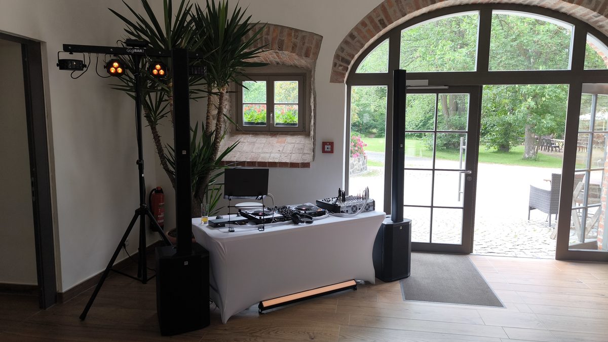 Eleganter DJ-Aufbau mit Lichttechnik vor einer großen Fensterfront