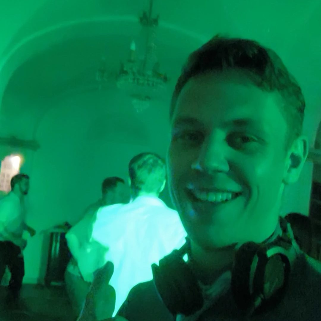 DJ Paul Funk mit Kopfhörern um den Hals, dahinter die Tanzfläche im grünen Licht