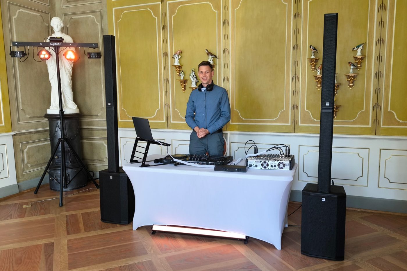DJ Paul Funk hinter seinem Pult in einem Schlosssaal mit goldener Wandvertäfelung, daneben Boxen und Lichttechnik